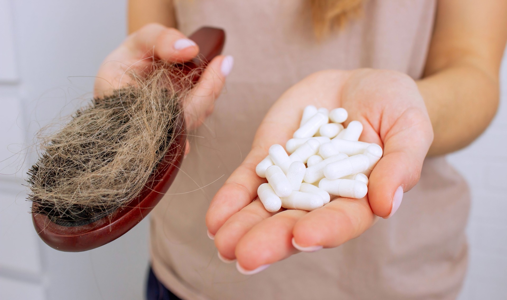 The woman holds a hair brush and vitamins from hair loss. Selective focus